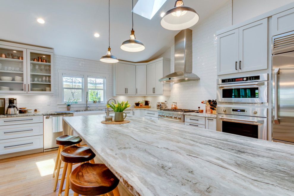 Photo of a large traditional l-shaped eat-in kitchen in Tampa with a farmhouse sink, shaker cabinets, grey cabinets, granite benchtops, white splashback, subway tile splashback, stainless steel appliances, bamboo floors, with island and vaulted.