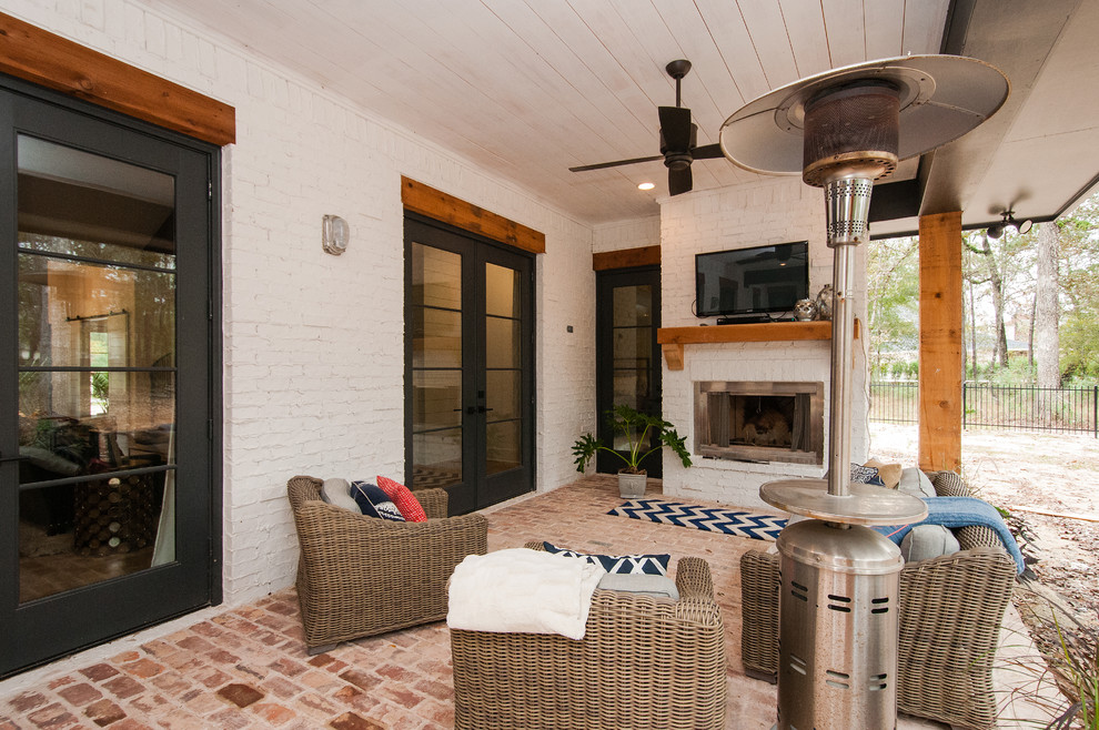 Large transitional backyard patio in Houston with a fire feature, brick pavers and a roof extension.