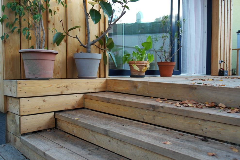 Diseño de terraza planta baja de estilo americano de tamaño medio en patio trasero y anexo de casas con barandilla de madera