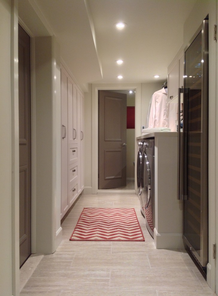 This is an example of a mid-sized contemporary galley dedicated laundry room in Montreal with shaker cabinets, grey cabinets, quartz benchtops, beige walls, porcelain floors and a side-by-side washer and dryer.
