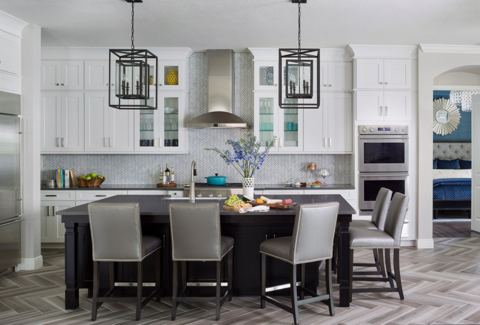 Inspiration for a large traditional l-shaped open plan kitchen in Tampa with a farmhouse sink, shaker cabinets, white cabinets, quartz benchtops, white splashback, marble splashback, stainless steel appliances, ceramic floors, with island, grey floor and black benchtop.