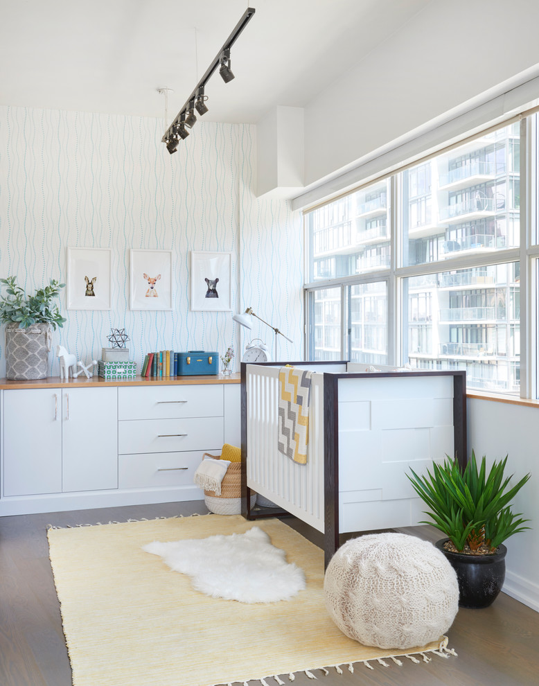 Small contemporary gender-neutral nursery in Toronto with white walls and light hardwood floors.
