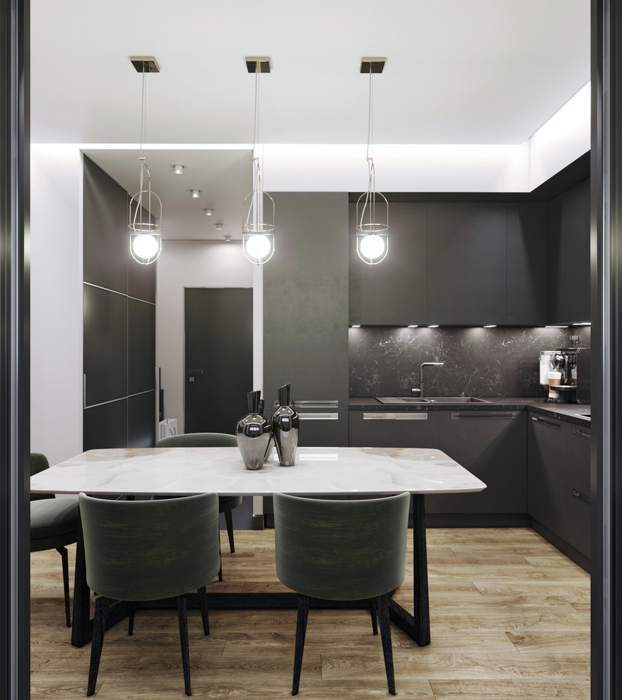This is an example of a small contemporary l-shaped open plan kitchen in Moscow with flat-panel cabinets, black cabinets, marble benchtops, black splashback, marble splashback, black appliances, laminate floors, no island, beige floor and black benchtop.