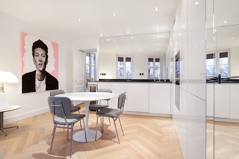 Inspiration for a mid-sized contemporary kitchen/dining combo in Paris with white walls and light hardwood floors.
