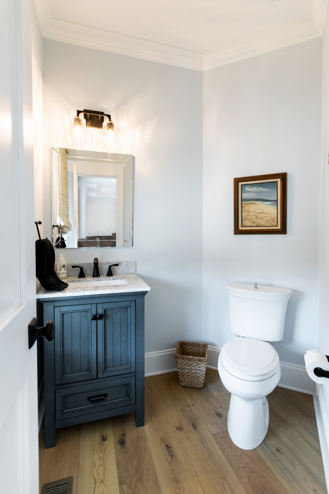 Aménagement d'un petit WC et toilettes classique avec des portes de placard bleues, WC séparés, un mur bleu, un sol en bois brun, un lavabo encastré, un plan de toilette gris et meuble-lavabo sur pied.