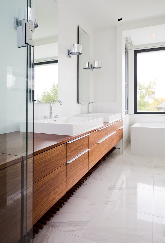 Contemporary bathroom in Vancouver with a freestanding tub, a vessel sink, marble floors, white floor and brown benchtops.