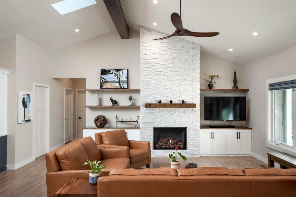 Inspiration for a large transitional formal and open concept medium tone wood floor, multicolored floor and exposed beam living room remodel in Other with beige walls, a standard fireplace, a stacked stone fireplace and a wall-mounted tv