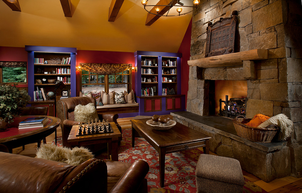 This is an example of a country living room in Sacramento with red walls, medium hardwood floors, a standard fireplace and a stone fireplace surround.
