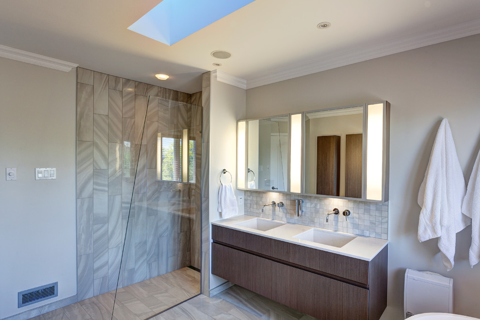 Inspiration for a mid-sized contemporary master bathroom in Montreal with an integrated sink, flat-panel cabinets, dark wood cabinets, engineered quartz benchtops, a freestanding tub, an open shower, gray tile, ceramic tile, grey walls and ceramic floors.