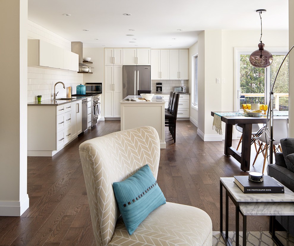 Example of a large transitional medium tone wood floor kitchen design in Toronto with a double-bowl sink, shaker cabinets, white cabinets, quartz countertops, white backsplash, ceramic backsplash, stainless steel appliances and an island