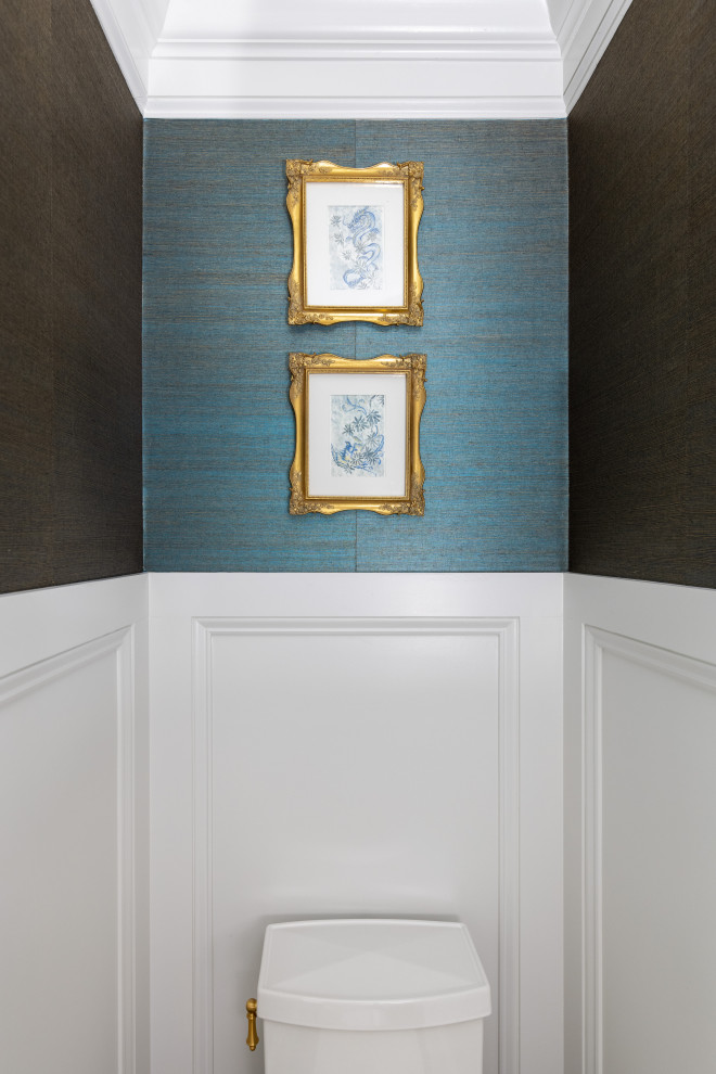 Example of a mid-sized transitional blue tile medium tone wood floor, brown floor and wallpaper powder room design with raised-panel cabinets, white cabinets, blue walls, an undermount sink, marble countertops, white countertops and a built-in vanity