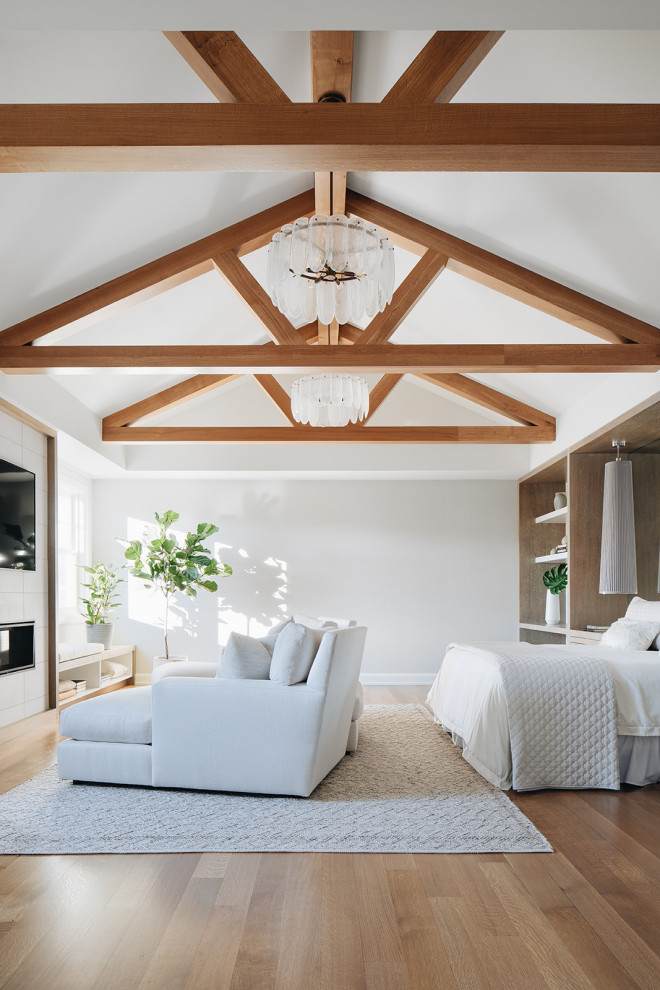 Photo of a large classic master bedroom in Chicago with white walls, light hardwood flooring, a standard fireplace, a tiled fireplace surround, brown floors and exposed beams.