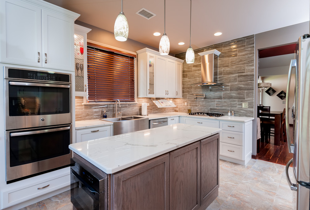 Enclosed kitchen - mid-sized transitional l-shaped porcelain tile and multicolored floor enclosed kitchen idea in Philadelphia with a farmhouse sink, shaker cabinets, white cabinets, quartzite countertops, brown backsplash, stone tile backsplash, stainless steel appliances, an island and white countertops