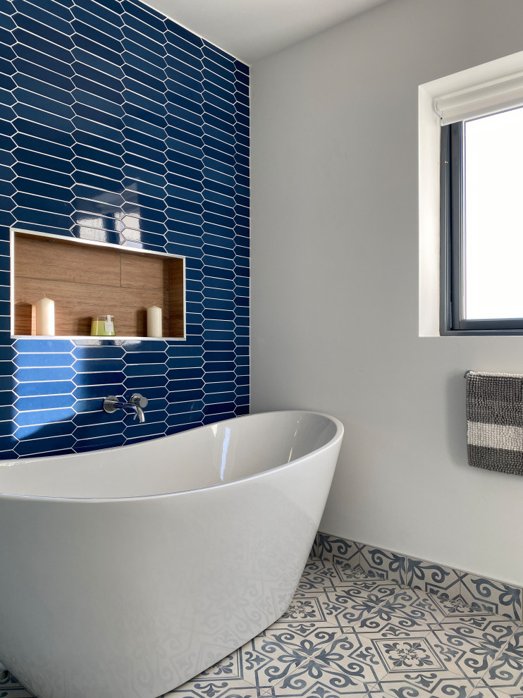 Идея дизайна: главная ванная комната среднего размера в современном стиле с фасадами островного типа, коричневыми фасадами, отдельно стоящей ванной, душем без бортиков, унитазом-моноблоком, белой плиткой, стеклянной плиткой, синими стенами, полом из керамической плитки, консольной раковиной, столешницей из бетона, желтым полом, открытым душем, белой столешницей, нишей, тумбой под одну раковину, подвесной тумбой и сводчатым потолком