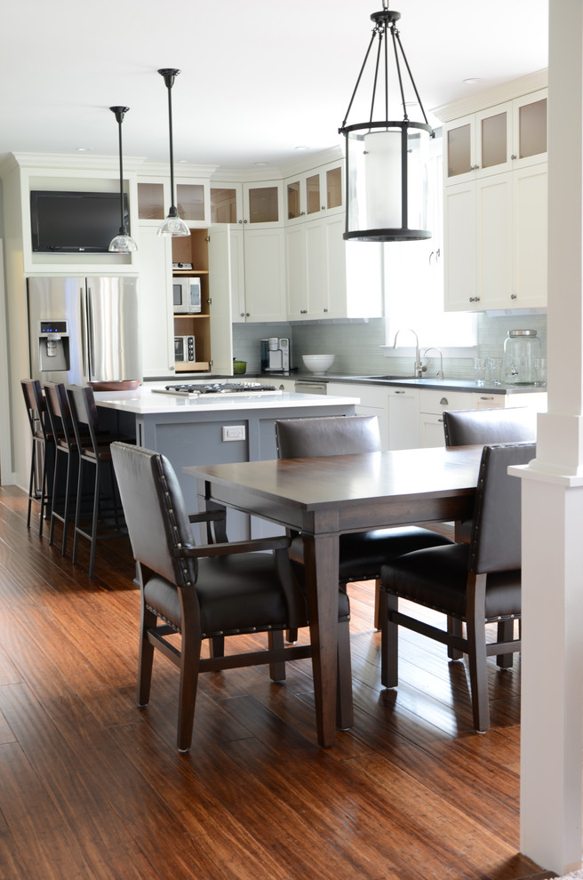 Inspiration for a mid-sized transitional l-shaped dark wood floor eat-in kitchen remodel with shaker cabinets, white cabinets, solid surface countertops, an island, a single-bowl sink, white backsplash, glass tile backsplash and stainless steel appliances