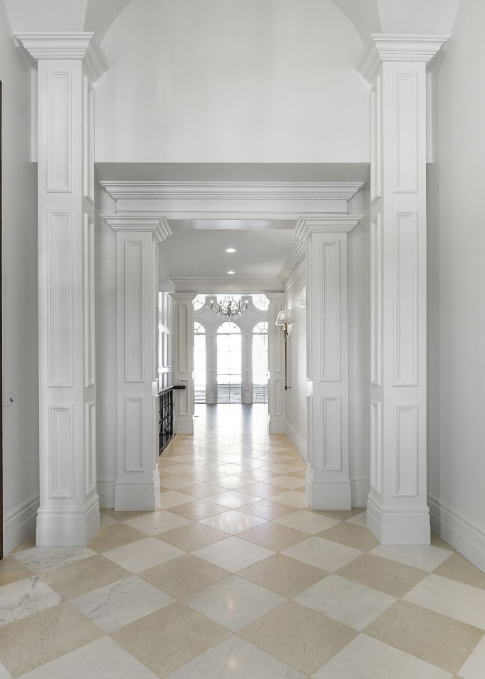 Immagine di un grande ingresso con pareti bianche, pavimento in marmo, una porta a due ante, una porta in legno scuro, pavimento bianco e soffitto a volta