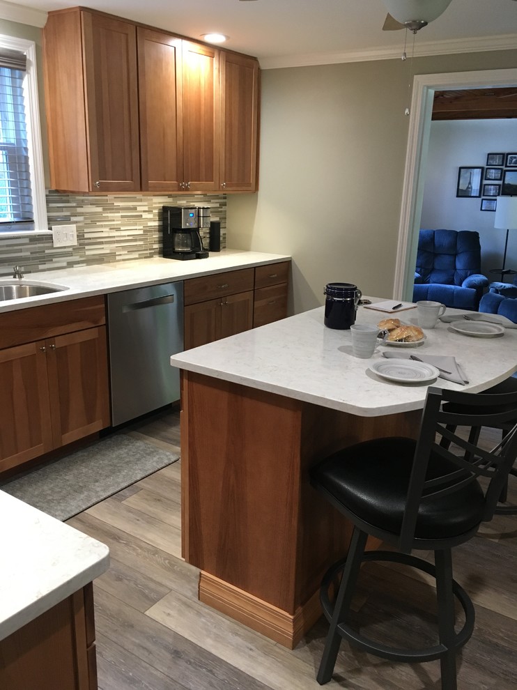 Inspiration for a mid-sized transitional l-shaped laminate floor and gray floor eat-in kitchen remodel in Boston with an undermount sink, shaker cabinets, light wood cabinets, quartz countertops, multicolored backsplash, glass sheet backsplash, stainless steel appliances, an island and white countertops