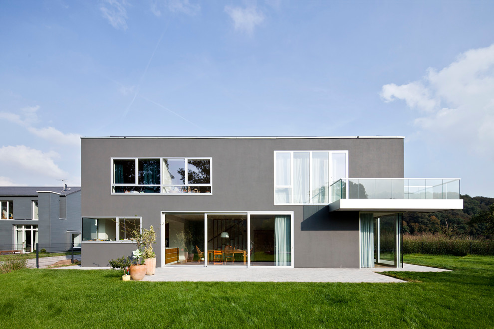 Photo of a mid-sized contemporary two-storey stucco grey exterior in Cologne with a flat roof.