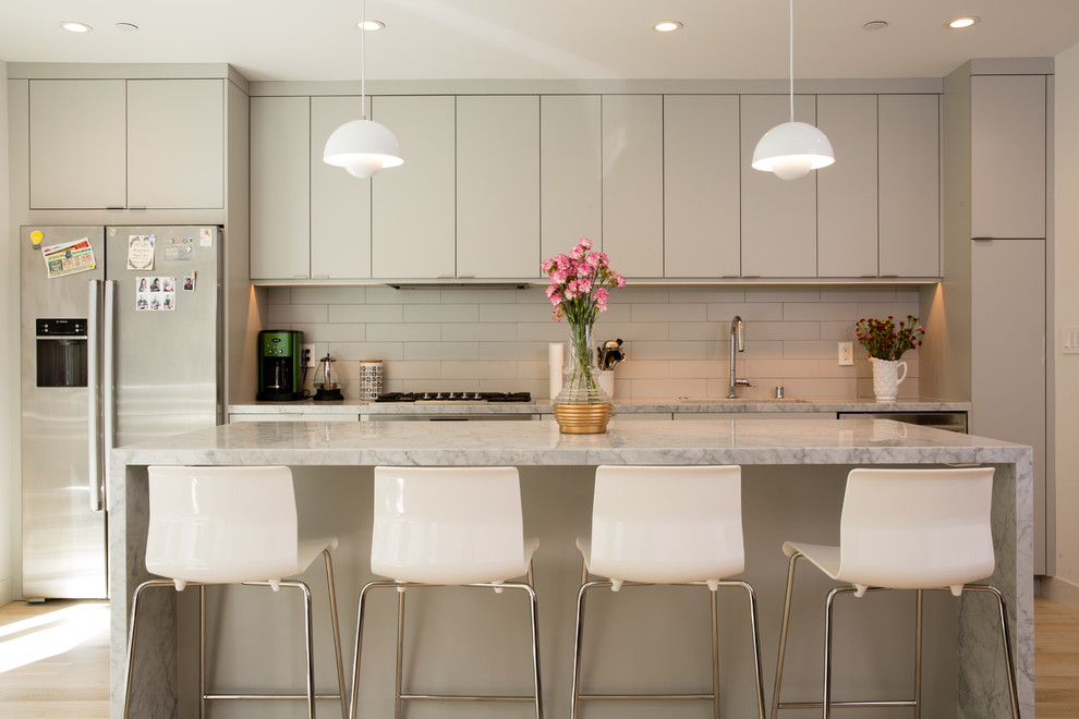 Design ideas for a contemporary kitchen in San Francisco with an undermount sink, flat-panel cabinets, grey cabinets, white splashback, subway tile splashback, stainless steel appliances, light hardwood floors and with island.