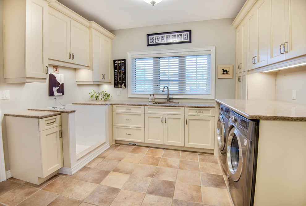 Inspiration for a large traditional u-shaped utility room in Toronto with an undermount sink, shaker cabinets, white cabinets, granite benchtops, white walls, porcelain floors, a side-by-side washer and dryer and beige floor.