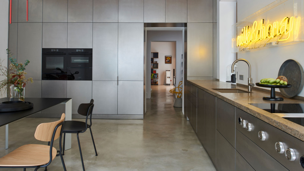 Esempio di una cucina lineare minimalista con ante lisce, ante in acciaio inossidabile, top in granito, paraspruzzi bianco, elettrodomestici neri, pavimento grigio, top beige e travi a vista