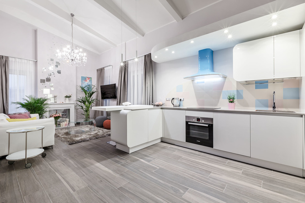 Photo of a large eclectic single-wall open plan kitchen in Milan with an undermount sink, flat-panel cabinets, white cabinets, solid surface benchtops, multi-coloured splashback, ceramic splashback, stainless steel appliances, porcelain floors and a peninsula.
