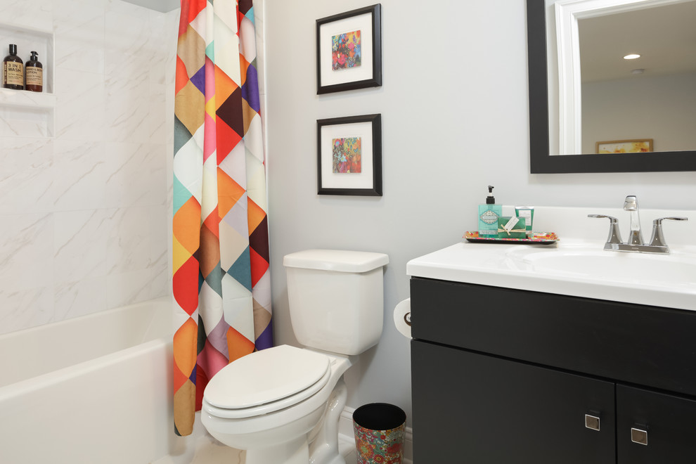 Transitional kids bathroom in Other with flat-panel cabinets, black cabinets, an alcove tub, an alcove shower, a two-piece toilet, gray tile, ceramic tile, grey walls, porcelain floors, an integrated sink, solid surface benchtops, grey floor and a shower curtain.