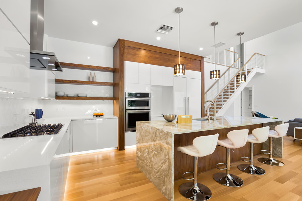 Design ideas for a large modern l-shaped open plan kitchen in Tampa with a double-bowl sink, flat-panel cabinets, quartzite benchtops, white splashback, ceramic splashback, stainless steel appliances, light hardwood floors, with island, beige floor and multi-coloured benchtop.
