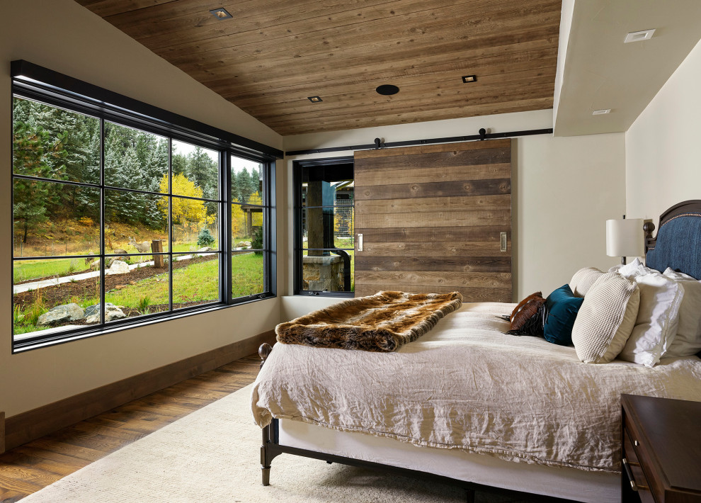 Inspiration for a large country master bedroom in Denver with white walls, brown floor and dark hardwood floors.