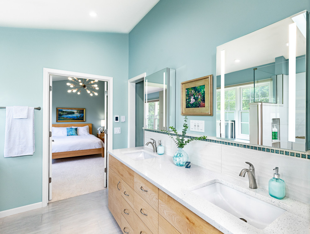 Cette image montre une grande salle de bain principale design en bois clair avec un carrelage blanc, un mur bleu, un sol gris, un plan de toilette blanc, meuble double vasque, meuble-lavabo encastré, un placard à porte plane, un bidet, des carreaux de céramique, un sol en carrelage de céramique, un lavabo encastré, un plan de toilette en quartz modifié, une cabine de douche à porte battante, une niche et un plafond voûté.