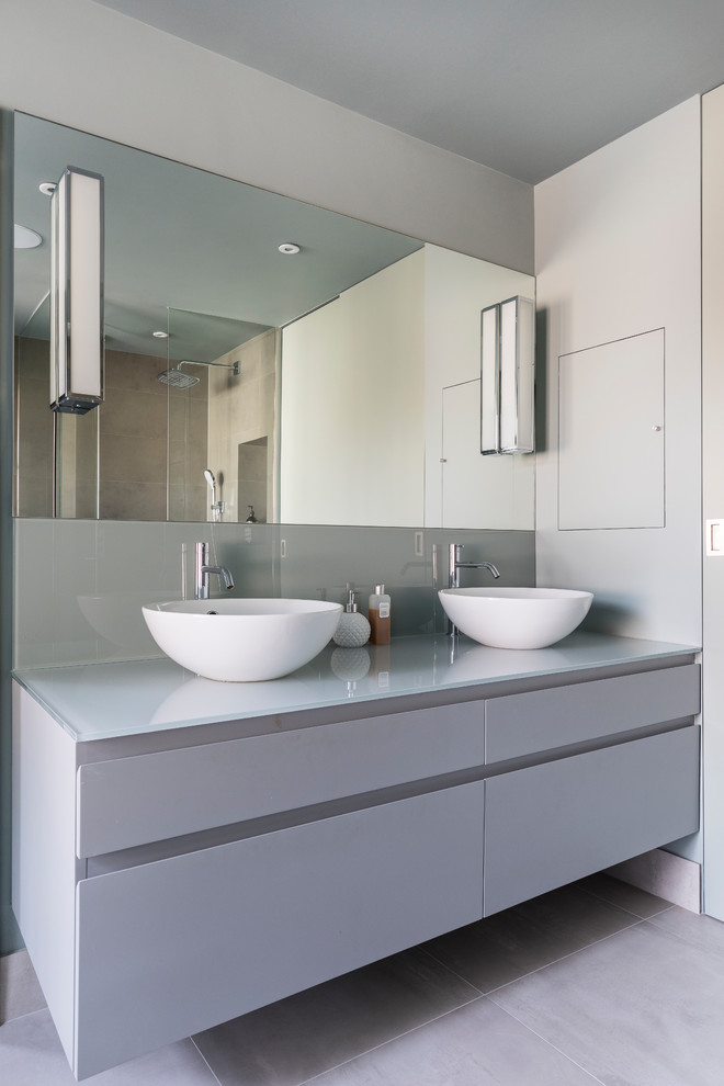 Inspiration for a mid-sized contemporary bathroom in London with flat-panel cabinets, grey cabinets, grey walls, a wall-mount sink and grey floor.