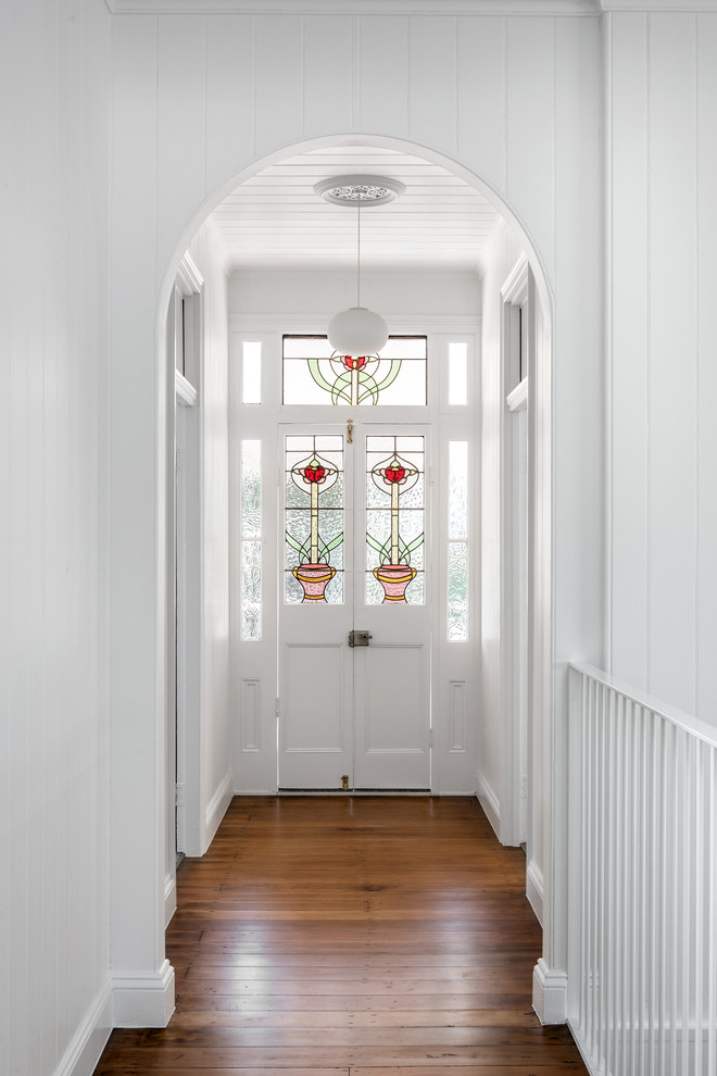 Inspiration for a beach style entry hall in Brisbane with white walls, medium hardwood floors, a double front door, a white front door and brown floor.