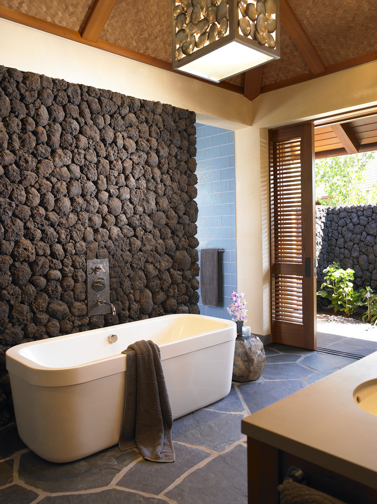 Tropical bathroom in Hawaii with a freestanding tub and slate floors.