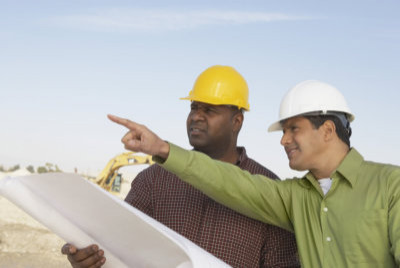 two men at construction site looking at plans