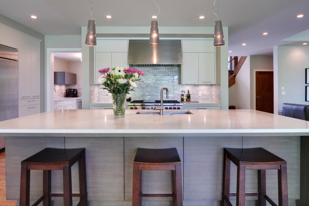 Transitional medium tone wood floor and brown floor kitchen photo in Calgary with an undermount sink, flat-panel cabinets, quartz countertops, gray backsplash, marble backsplash, stainless steel appliances and an island