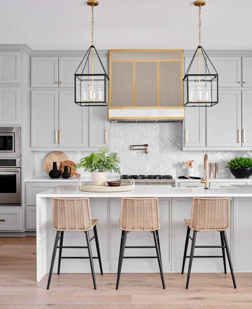 Open concept kitchen - mid-sized transitional l-shaped light wood floor and gray floor open concept kitchen idea in Austin with a farmhouse sink, shaker cabinets, gray cabinets, quartz countertops, gray backsplash, marble backsplash, paneled appliances, an island and white countertops