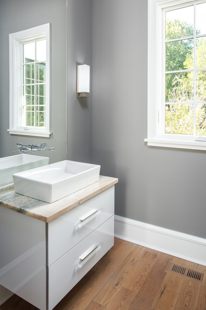 Design ideas for a transitional bathroom in Charlotte with flat-panel cabinets, white cabinets, a wall-mount toilet, white tile, marble, white walls, light hardwood floors, a vessel sink, quartzite benchtops and brown floor.