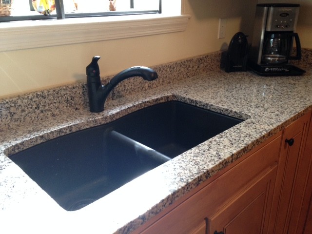 Example of a small transitional u-shaped medium tone wood floor home design design with an undermount sink, raised-panel cabinets, medium tone wood cabinets, granite countertops, black appliances and no island