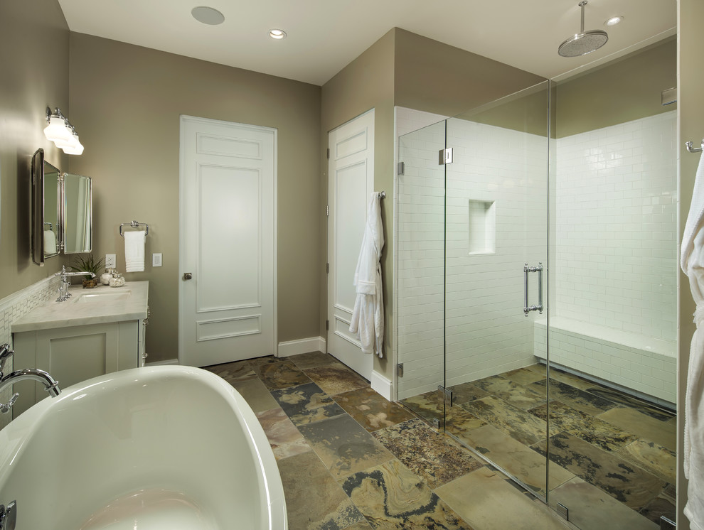 Photo of a mid-sized transitional master bathroom in Phoenix with white cabinets, marble benchtops, an undermount sink, a freestanding tub, a wall-mount toilet, white tile, ceramic tile, grey walls and slate floors.