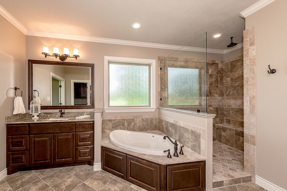 Design ideas for a mid-sized country 3/4 bathroom in Austin with shaker cabinets, medium wood cabinets, an alcove tub, a shower/bathtub combo, a two-piece toilet, brown tile, travertine, beige walls, brick floors, an undermount sink, granite benchtops, brown floor and an open shower.