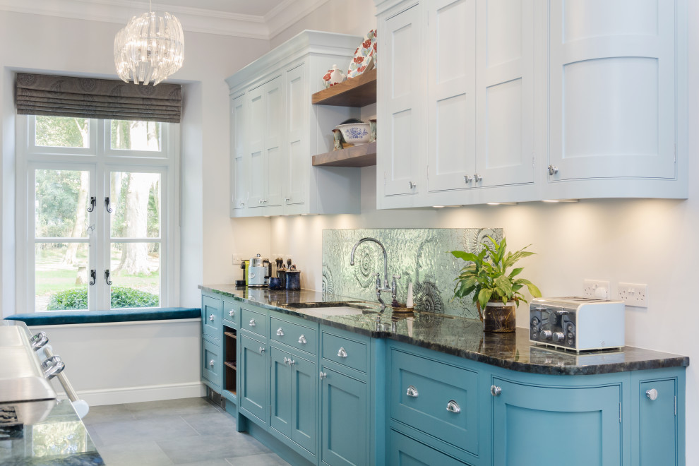 Inspiration for a large transitional single-wall open plan kitchen in Other with a drop-in sink, recessed-panel cabinets, blue cabinets, granite benchtops, coloured appliances, ceramic floors, black benchtop, blue splashback, glass sheet splashback and grey floor.