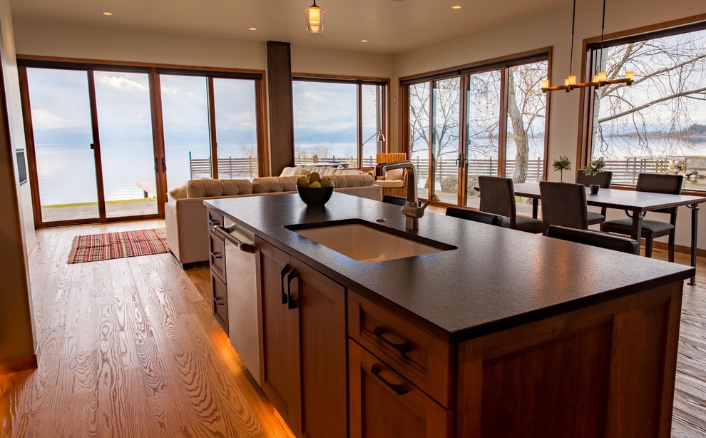 Example of a large mountain style l-shaped light wood floor and brown floor open concept kitchen design with an undermount sink, quartzite countertops, stainless steel appliances, an island, shaker cabinets, dark wood cabinets, brown backsplash and ceramic backsplash
