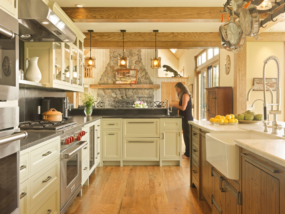 Inspiration for a country open plan kitchen in Burlington with recessed-panel cabinets, beige cabinets, with island, a farmhouse sink, grey splashback, stainless steel appliances and medium hardwood floors.