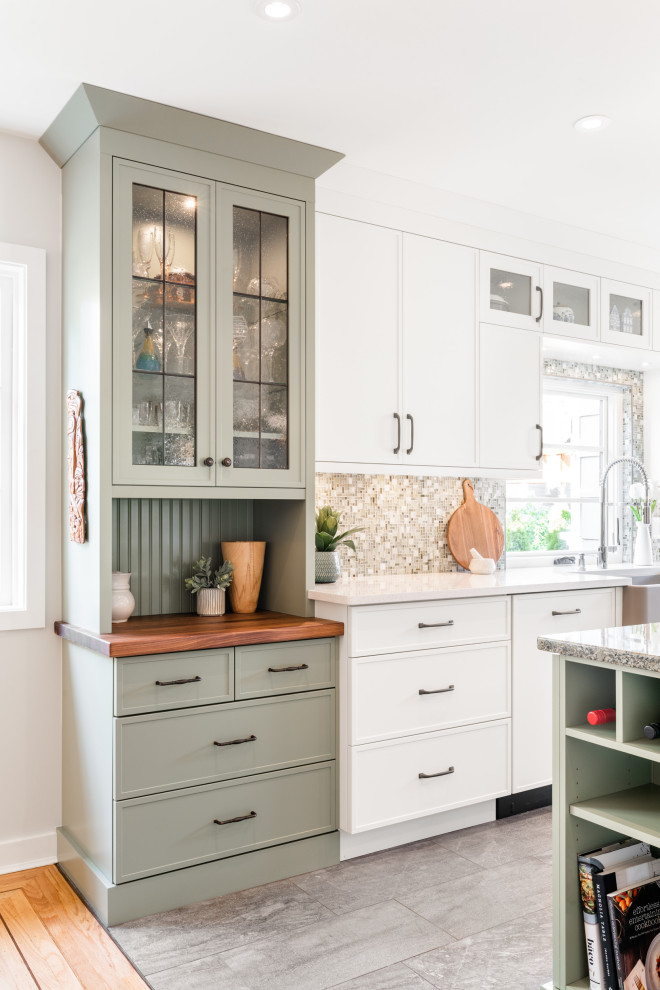 This is an example of a small country single-wall eat-in kitchen in Vancouver with a farmhouse sink, shaker cabinets, green cabinets, wood benchtops, multi-coloured splashback, mosaic tile splashback, stainless steel appliances, vinyl floors, with island, grey floor and brown benchtop.