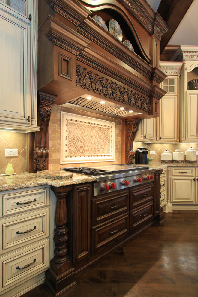 This is an example of an expansive traditional u-shaped eat-in kitchen in Atlanta with an undermount sink, raised-panel cabinets, distressed cabinets, granite benchtops, beige splashback, stone tile splashback, panelled appliances, dark hardwood floors and multiple islands.
