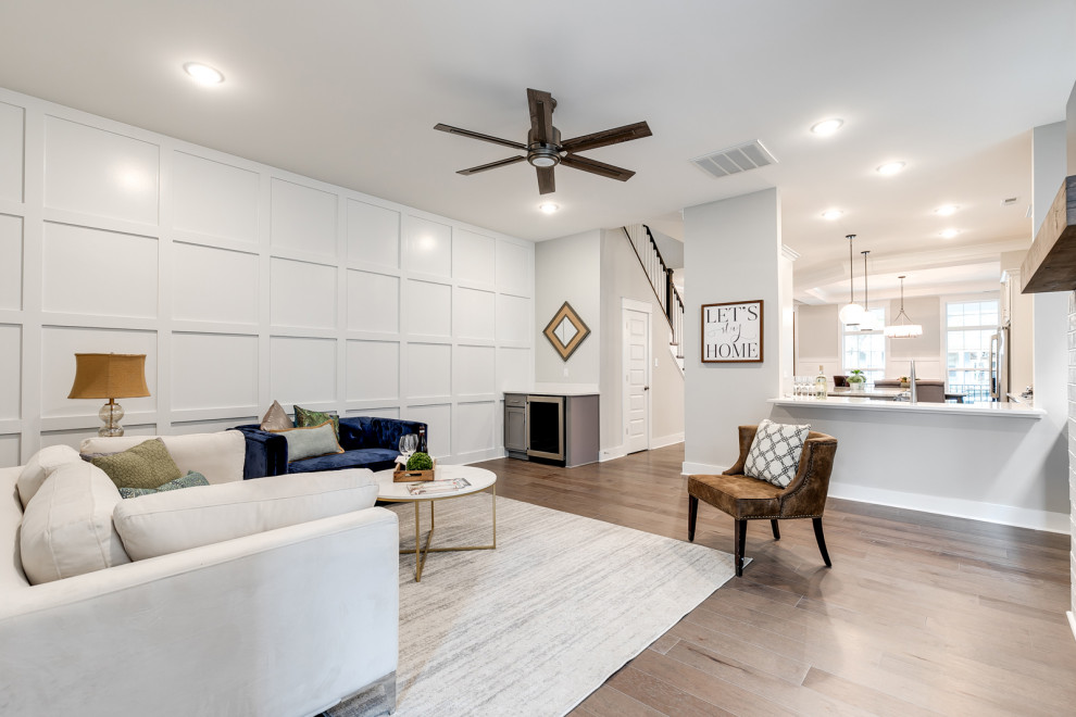 Inspiration for a mid-sized traditional open concept family room in Richmond with white walls, medium hardwood floors, a wall-mounted tv, brown floor, decorative wall panelling, a ribbon fireplace and a brick fireplace surround.