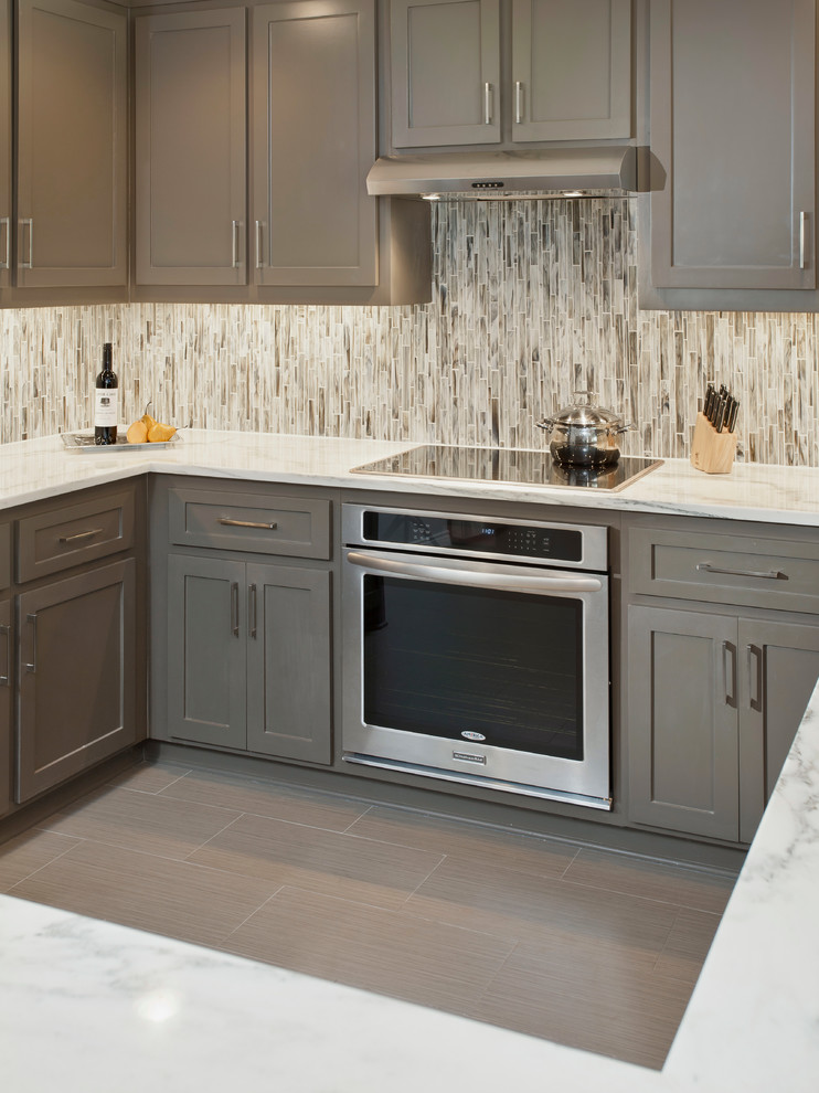 This is an example of a transitional eat-in kitchen in Dallas with shaker cabinets, grey cabinets, marble benchtops, grey splashback, stainless steel appliances, porcelain floors, no island, mosaic tile splashback, brown floor and white benchtop.