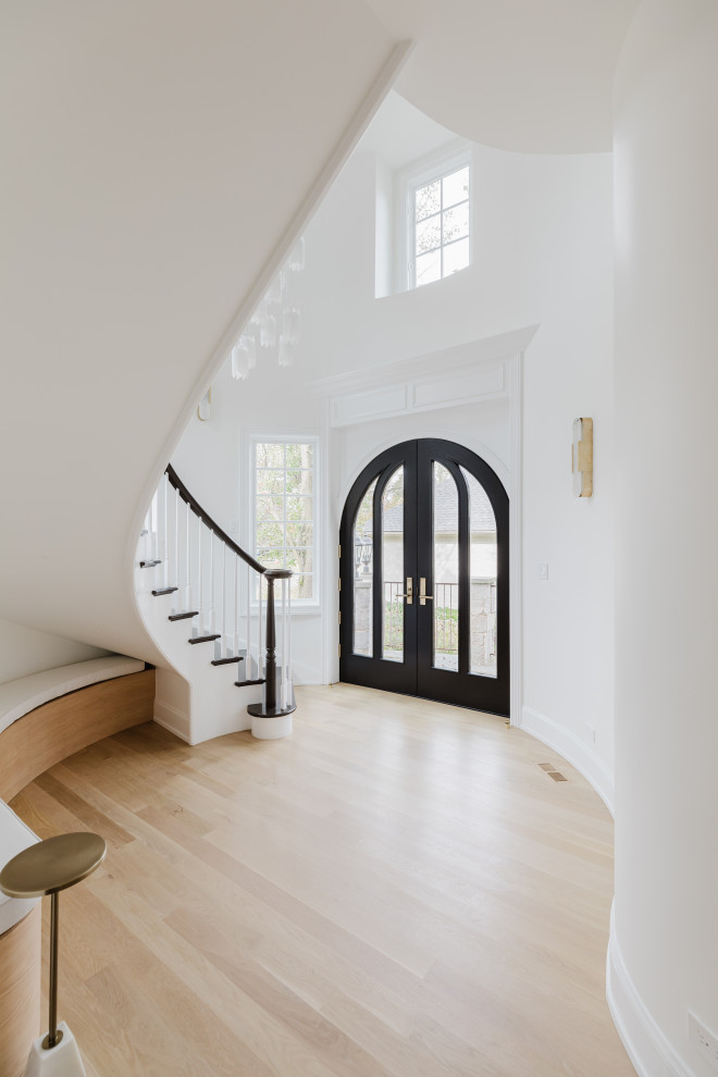 Elegant Home Interior Entrance With Curved Staircase and Black Double Doors