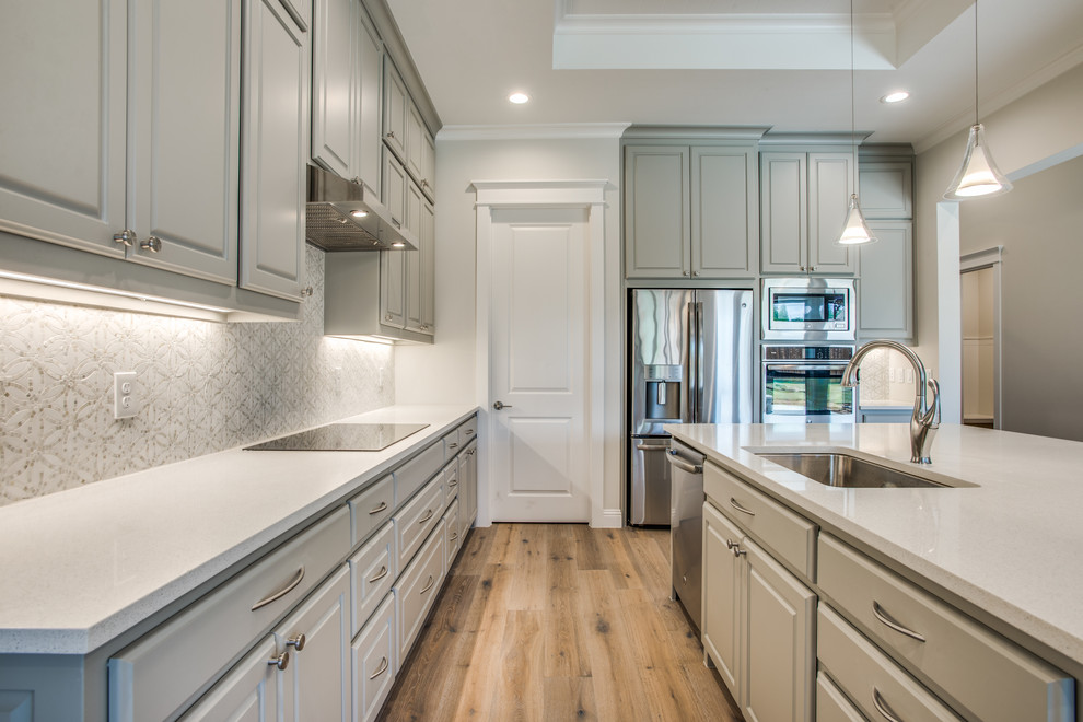 Design ideas for a large transitional l-shaped open plan kitchen in Dallas with an undermount sink, raised-panel cabinets, grey cabinets, stainless steel appliances, plywood floors and with island.