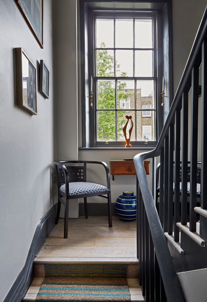 Photo of a transitional wood u-shaped staircase in London with wood risers.